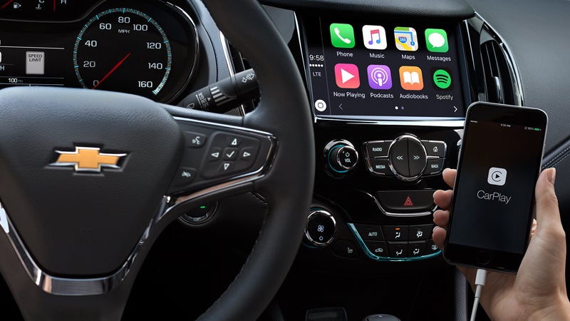 A close-up of the Chevrolet Cruze's steering wheel and infotainment screen displaying Apple CarPlay