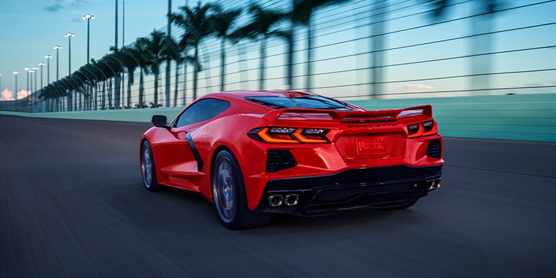 A rear view of a red Chevrolet Corvette Stingray driving on a bridge at dusk