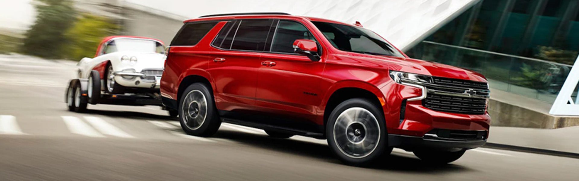 A red 2024 Chevrolet Tahoe towing a trailer on the highway