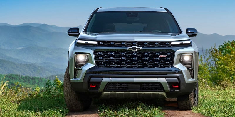 A front view of the 2024 Chevrolet Traverse parked on grass with mountains in the background