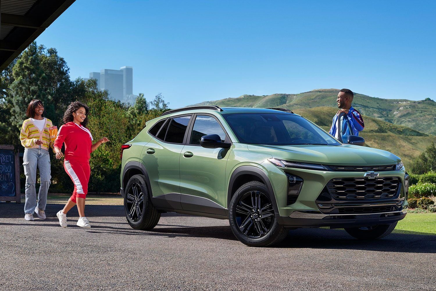 : A green 2024 Chevrolet Trax parked beside hills with a couple standing near the car