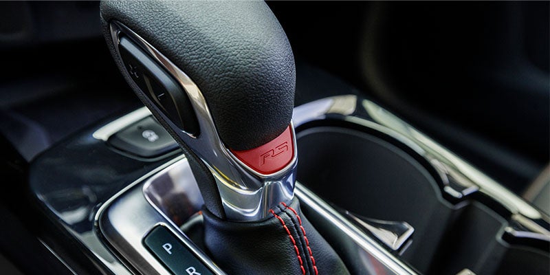 Close-up of a gear shift lever with red stitching inside a vehicle