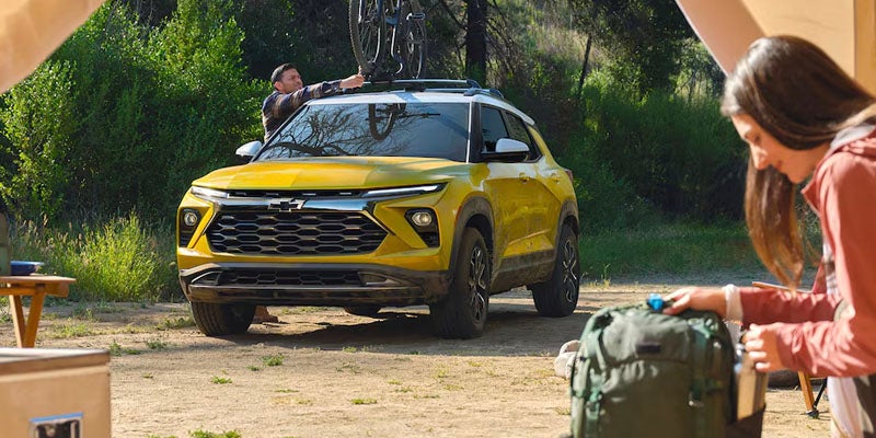 Man removing a bicycle from the yellow 2025 Chevrolet Trailblazer